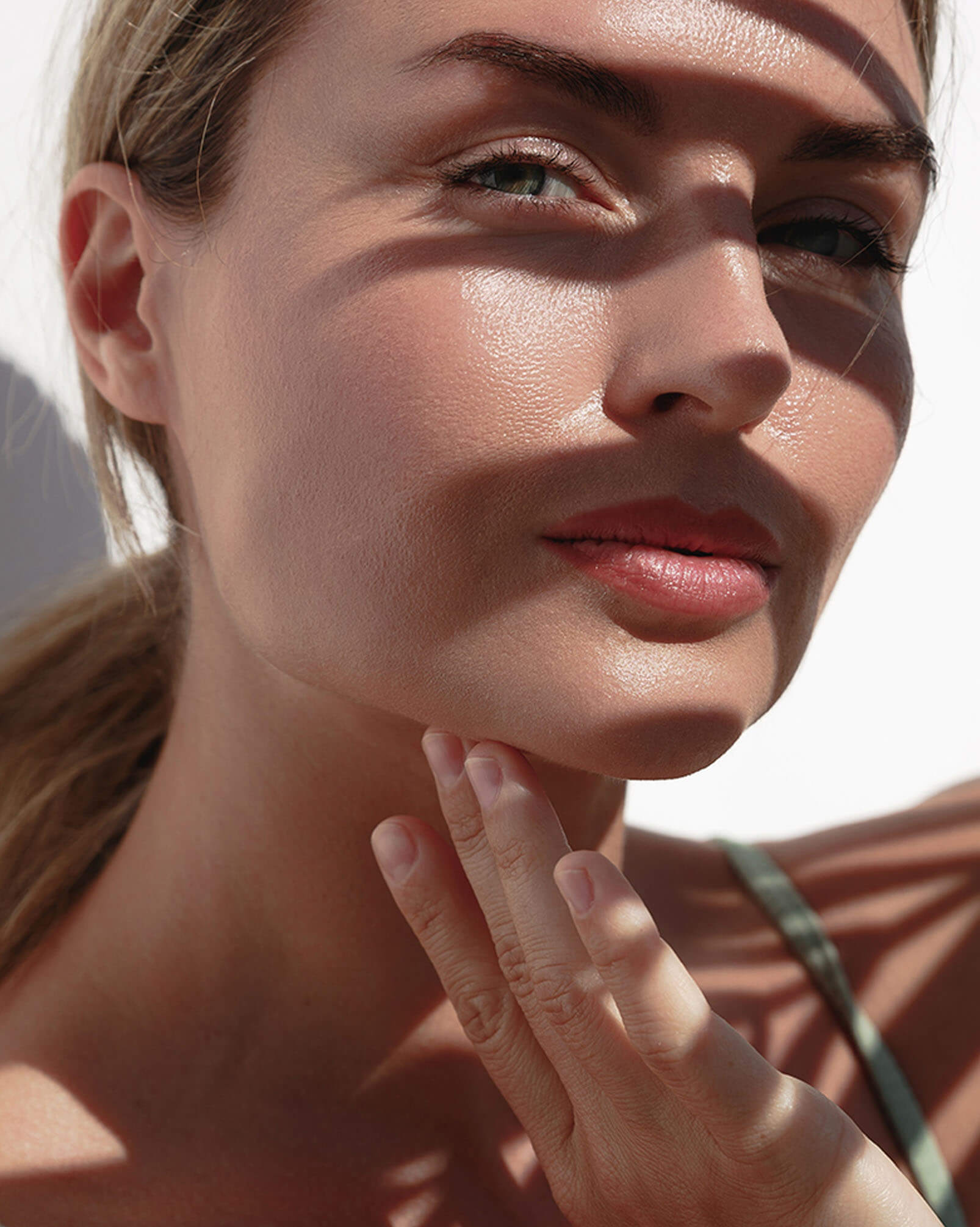 woman touching her jaw and the other hand casing shadows on her face