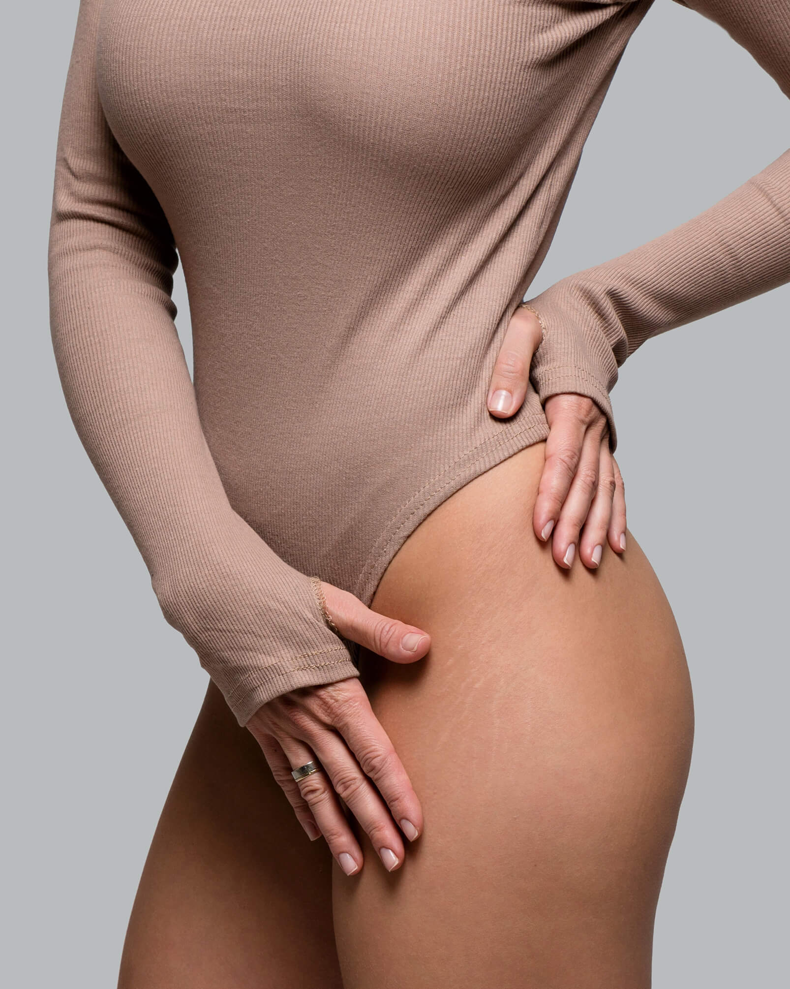 woman in slim tan long sleeve top touching her leg